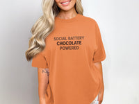 Orange t-shirt with text "SOCIAL BATTERY CHOCOLATE POWERED".