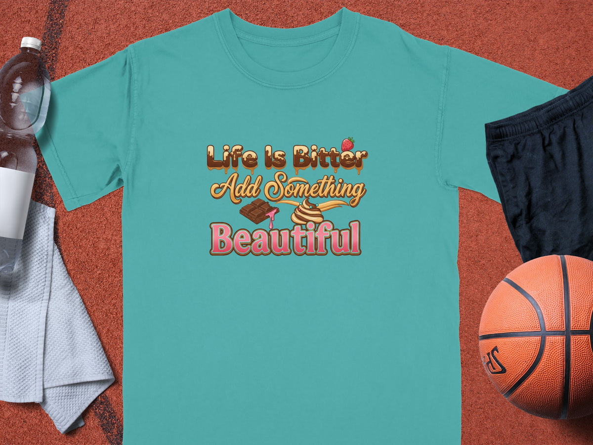 Teal t-shirt with text "Life Is Bitter Add Something Beautiful" and graphics.