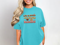 Turquoise t-shirt with text "Life is Bitter Add Something Beautiful" and dessert graphic.