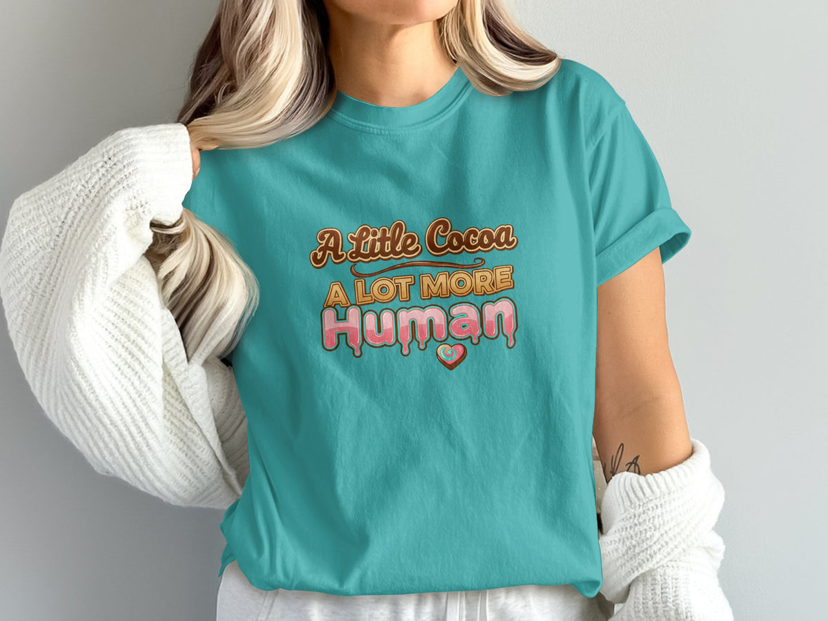 Teal t-shirt with "A Little Cocoa A LOT MORE Human" text and heart design.