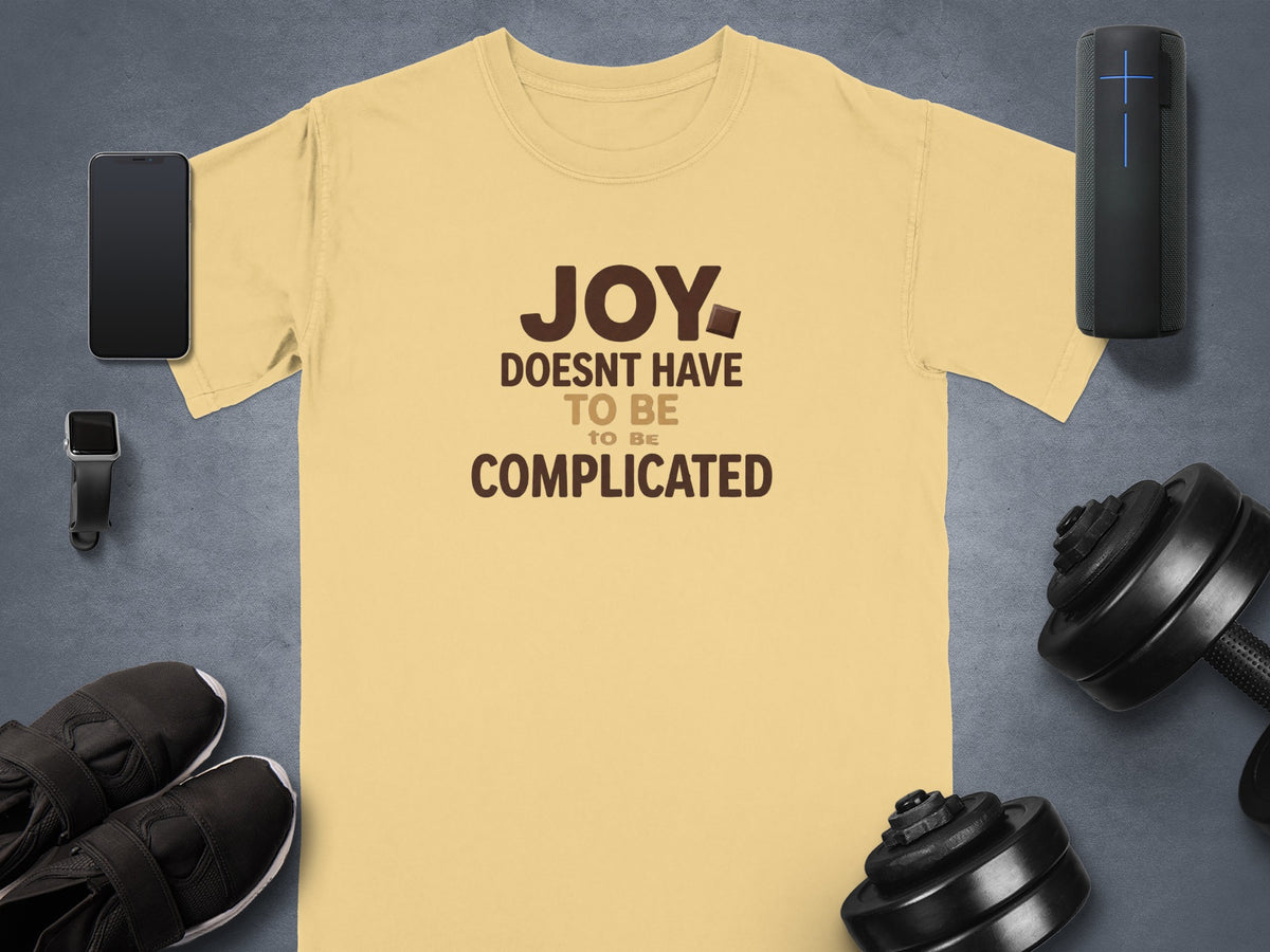Yellow t-shirt with brown text reading "JOY DOESNT HAVE TO BE COMPLICATED"