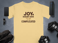Yellow t-shirt with brown text reading "JOY DOESNT HAVE TO BE COMPLICATED"