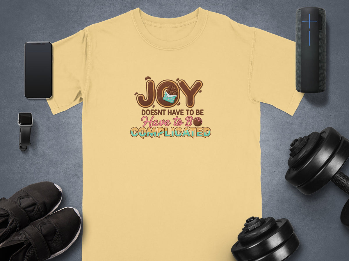 Yellow t-shirt with "JOY DOESN'T HAVE TO BE COMPLICATED" text and chocolate graphic.