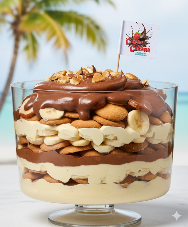 Layered dessert in a glass bowl with chocolate, nuts, and bananas, set against a blurred beach background.