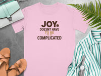 Pink t-shirt with "Joy Doesn't Have to Be Complicated" text and a chocolate square.