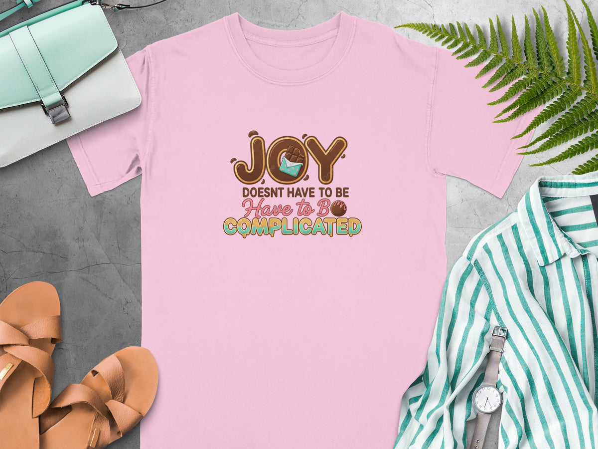 Pink t-shirt with "JOY DOESN'T HAVE TO BE Have to Be COMPLICATED" text and chocolate design.